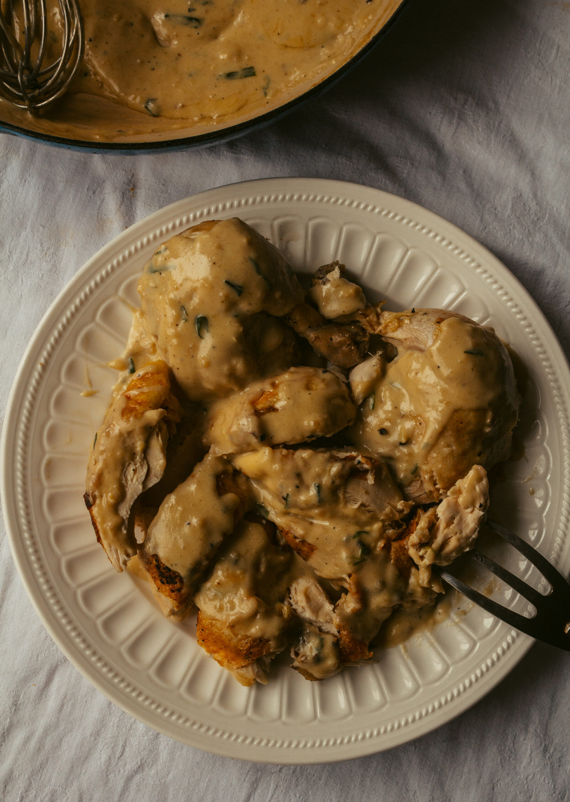 picture of sliced roast chicken on a plate with tarragon sauce poured over it.