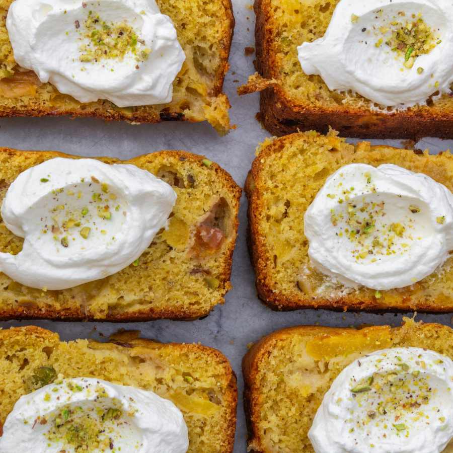 picture of sliced peach and pistachio cake with whipped cream on each slice.