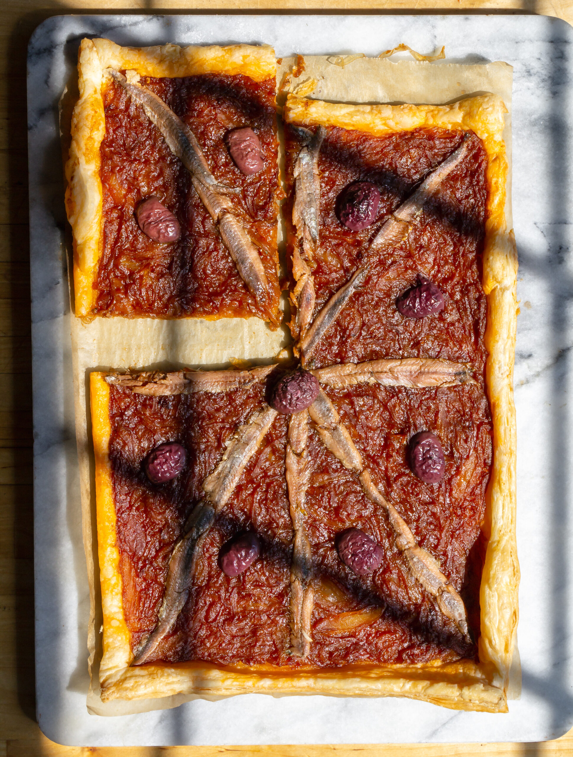 picture of a pissaladiere with one piece cut into a quarter.